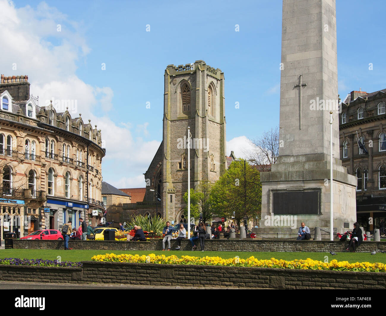 Le persone che si godono il sole su una giornata di primavera presso la chiesa e il cenotafio nel centro di Harrogate, nello Yorkshire, Inghilterra, Regno Unito. Foto Stock