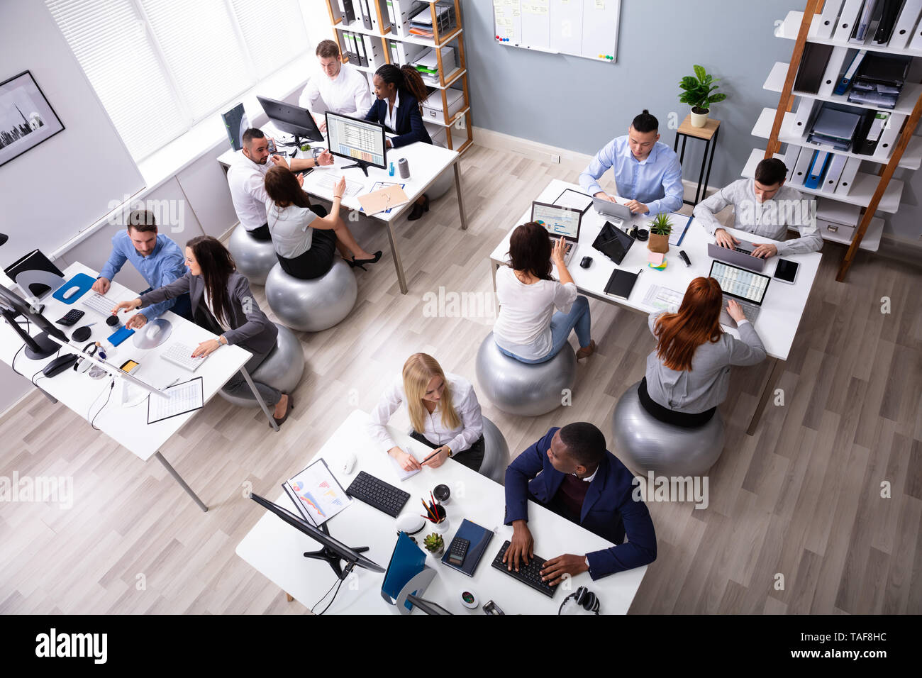Gruppo di multi-etnico imprenditori seduti sulla palla Fitness avente discutendo mentre lavoro in ufficio Foto Stock