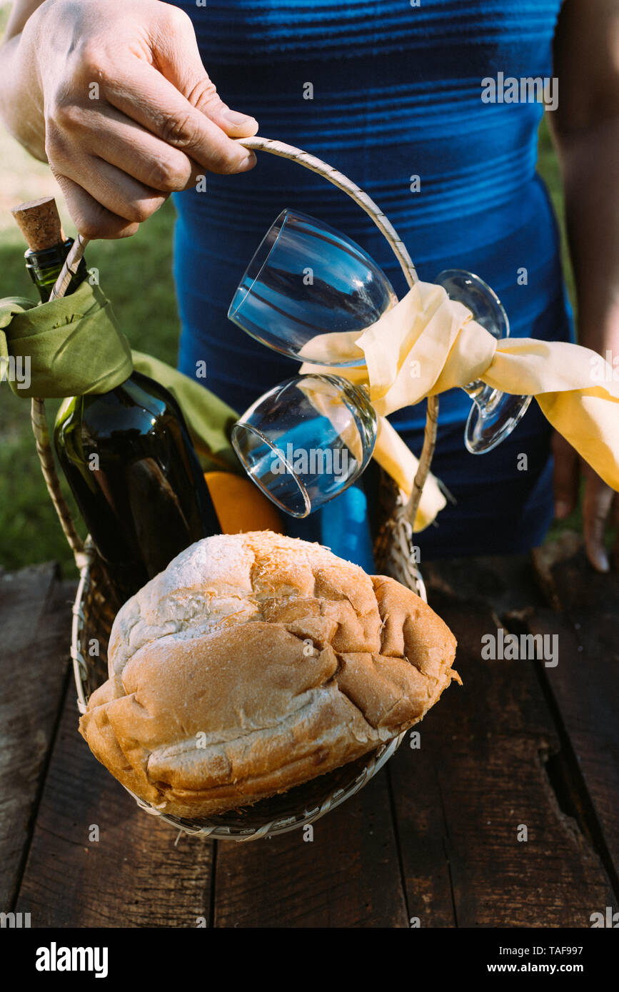 Pane casereccio, bottiglia di vino e due bicchieri in un cesto su una tavola in legno rustico Foto Stock