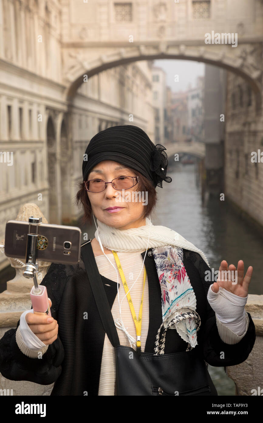 Un turista in posa per una foto selfie davanti al Ponte dei Sospiri a Venezia, Italia. Foto Stock