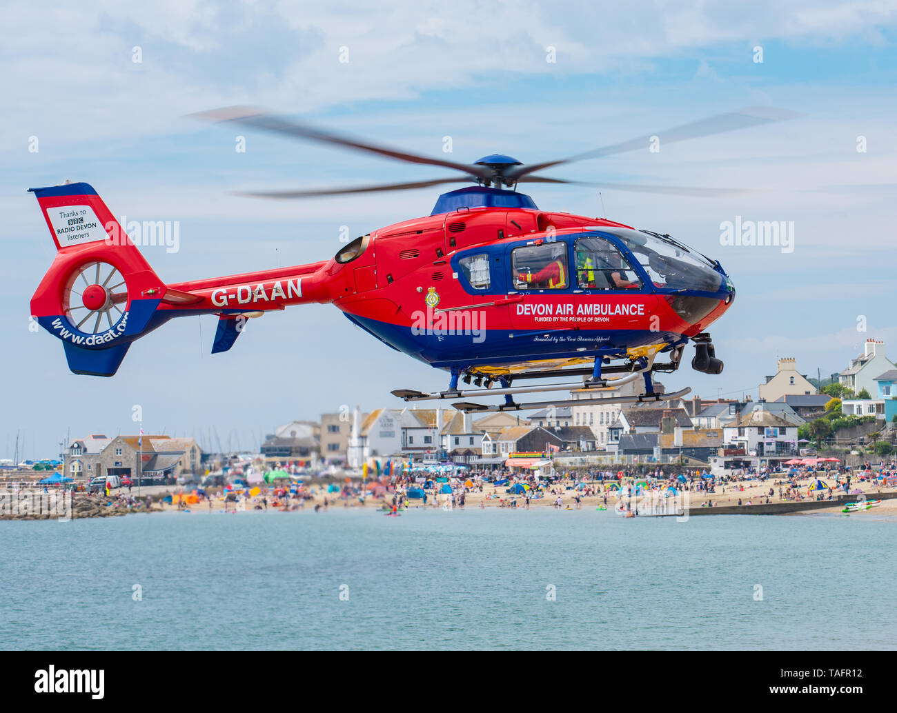 Lyme Regis, Dorset, Regno Unito. 25 maggio 2019. Devon Air Ambulance elicottero atterra sulla spiaggia affollata a Lyme Regis. L'elicottero decolla dall'affollata spiaggia con un paziente a bordo. Credito: Celia McMahon/Alamy Live News. Foto Stock