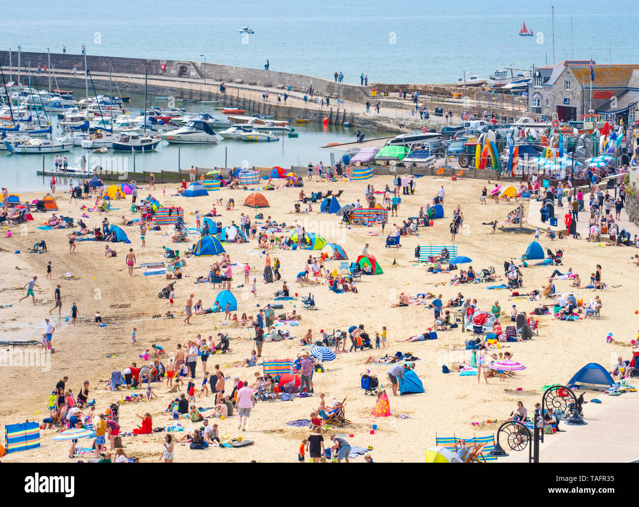 Lyme Regis, Dorset, Regno Unito. 25 maggio 2019. Meteo REGNO UNITO: folle di turisti e visitatori accorrono per la spiaggia di Lyme Regis a crogiolarvi al sole caldo come il resort costiero sfrigola su il giorno più caldo dell'anno finora. Il sabato è impostata in modo da essere il più soleggiato giorno di fine maggio weekend festivo. Credito: Celia McMahon/Alamy Live News. Credito: Celia McMahon/Alamy Live News Foto Stock