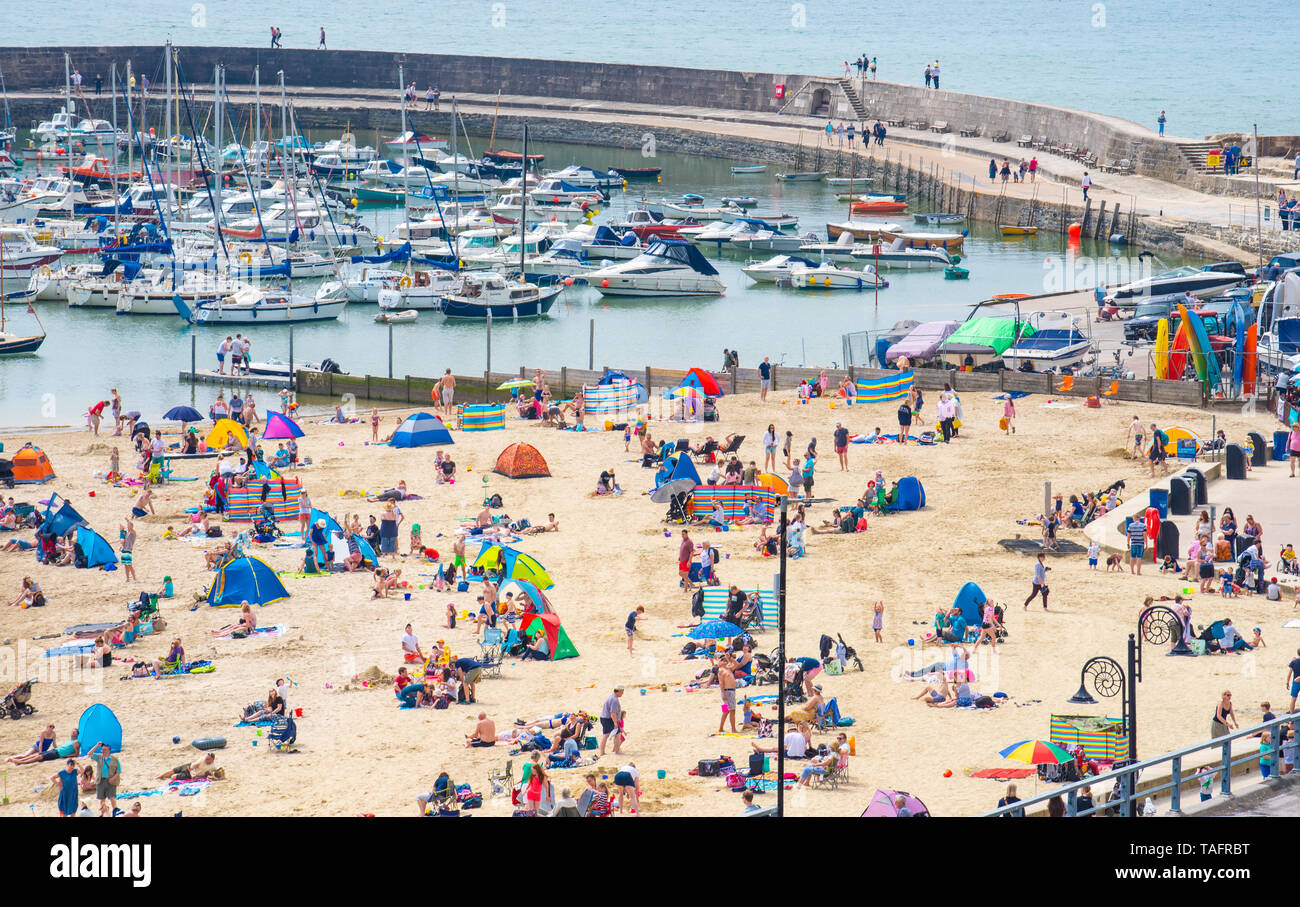 Lyme Regis, Dorset, Regno Unito. 25 maggio 2019. Meteo REGNO UNITO: folle di turisti e visitatori accorrono per la spiaggia di Lyme Regis a crogiolarvi al sole caldo come il resort costiero sfrigola su il giorno più caldo dell'anno finora. Il sabato è impostata in modo da essere il più soleggiato giorno di fine maggio weekend festivo. Credito: Celia McMahon/Alamy Live News. Credito: Celia McMahon/Alamy Live News Foto Stock