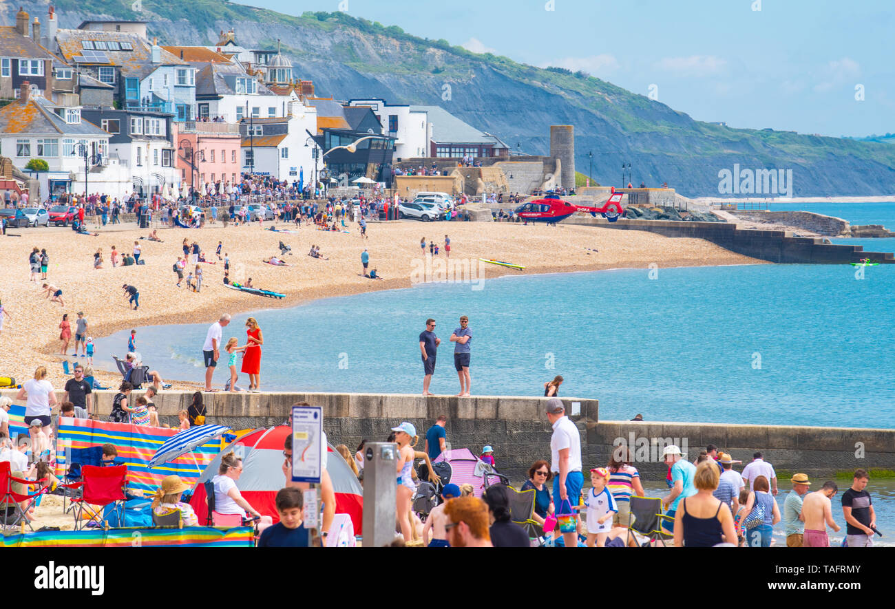 Lyme Regis, Dorset, Regno Unito. 25 maggio 2019. Meteo REGNO UNITO: folle di turisti e visitatori accorrono per la spiaggia di Lyme Regis a crogiolarvi al sole caldo come il resort costiero sfrigola su il giorno più caldo dell'anno finora. Il sabato è impostata in modo da essere il più soleggiato giorno di fine maggio weekend festivo. Credito: Celia McMahon/Alamy Live News. Credito: Celia McMahon/Alamy Live News Foto Stock
