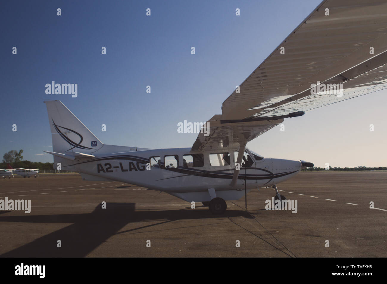 Maun, Botswana, Ottobre 2014: aerei Cessna parcheggiato permanente presso la pista di atterraggio dell'aeroporto locale durante il sunrise Foto Stock