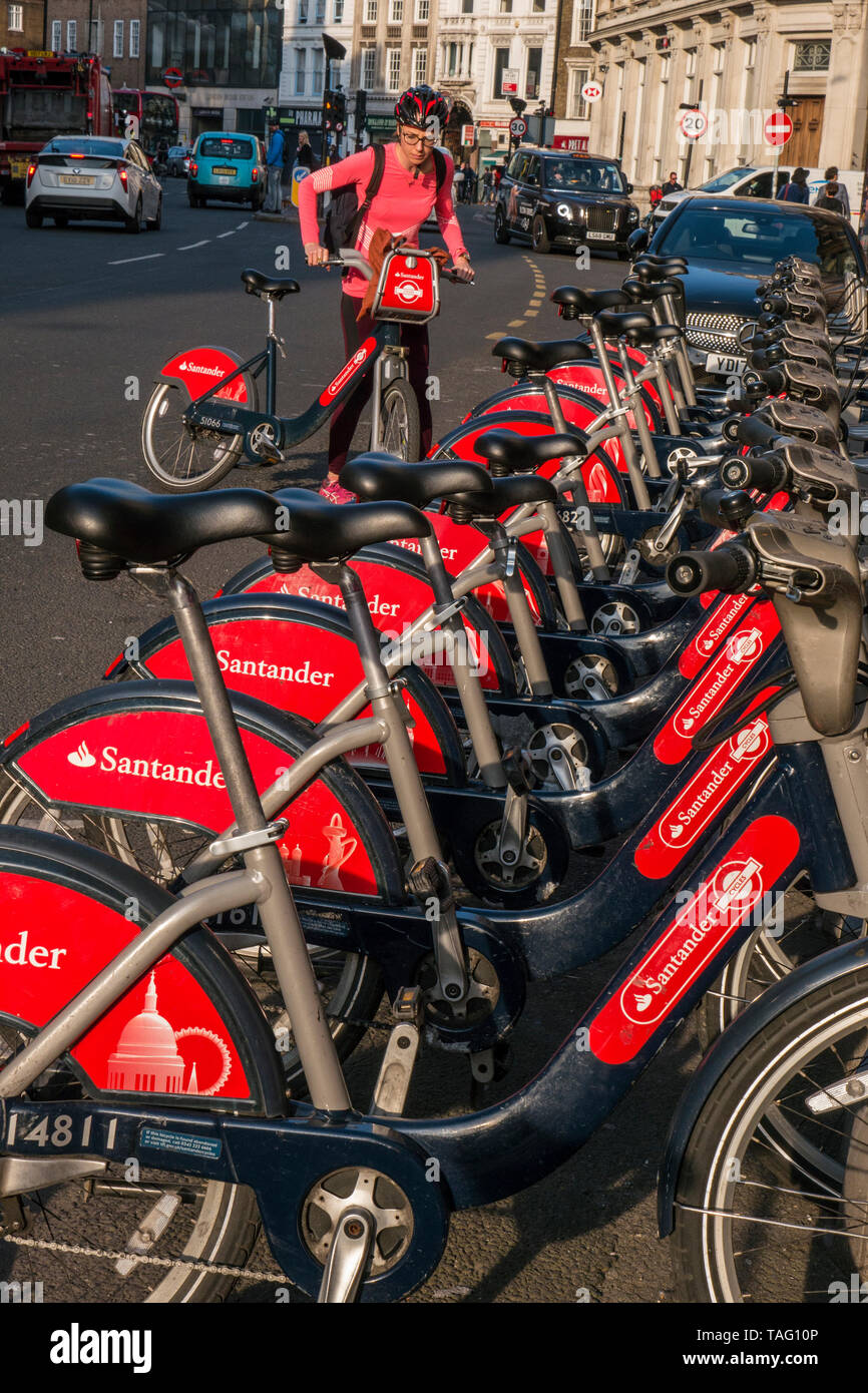 TFL Santander sponsorizzato Londra noleggio bici rosso a Southwark Street con ciclista femminile che indossa un casco di sicurezza circa per iniziare il suo noleggio dalla stazione di aggancio del terminale di bici. Trasporto per Londra Southwark London UK Foto Stock
