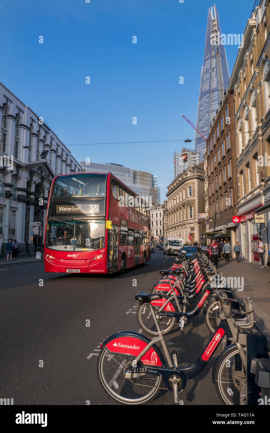 Biciclette Londra TFL Santander sponsorizzata linea rossa noleggio biciclette biciclette a Southwark Street con autobus rosso Londra e l'edificio Shard dietro. Stazione di aggancio per il terminale per biciclette. Trasporto per Londra Southwark London UK Foto Stock