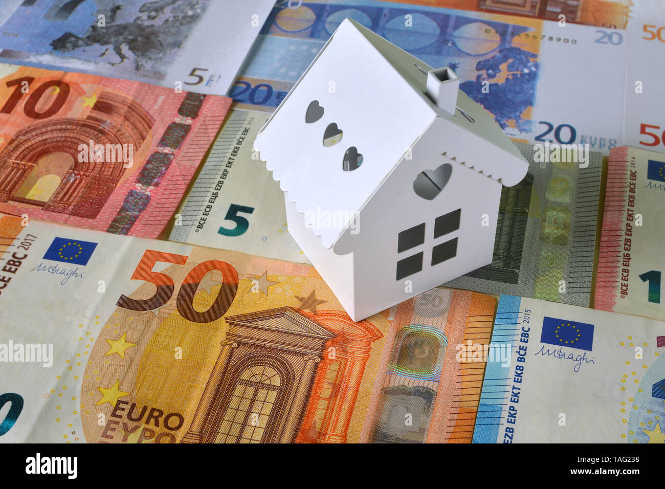 Piccola casa bianca su uno sfondo di banconote in euro. Foto Stock