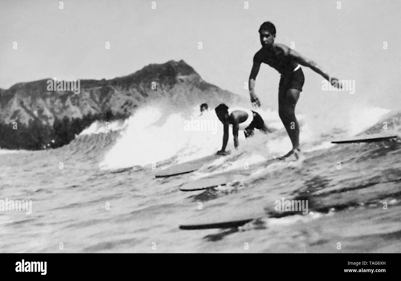 Surfisti cavalcare un onda presso la spiaggia di Waikiki a Honolulu, Territorio delle Hawaii, c1932. Foto Stock