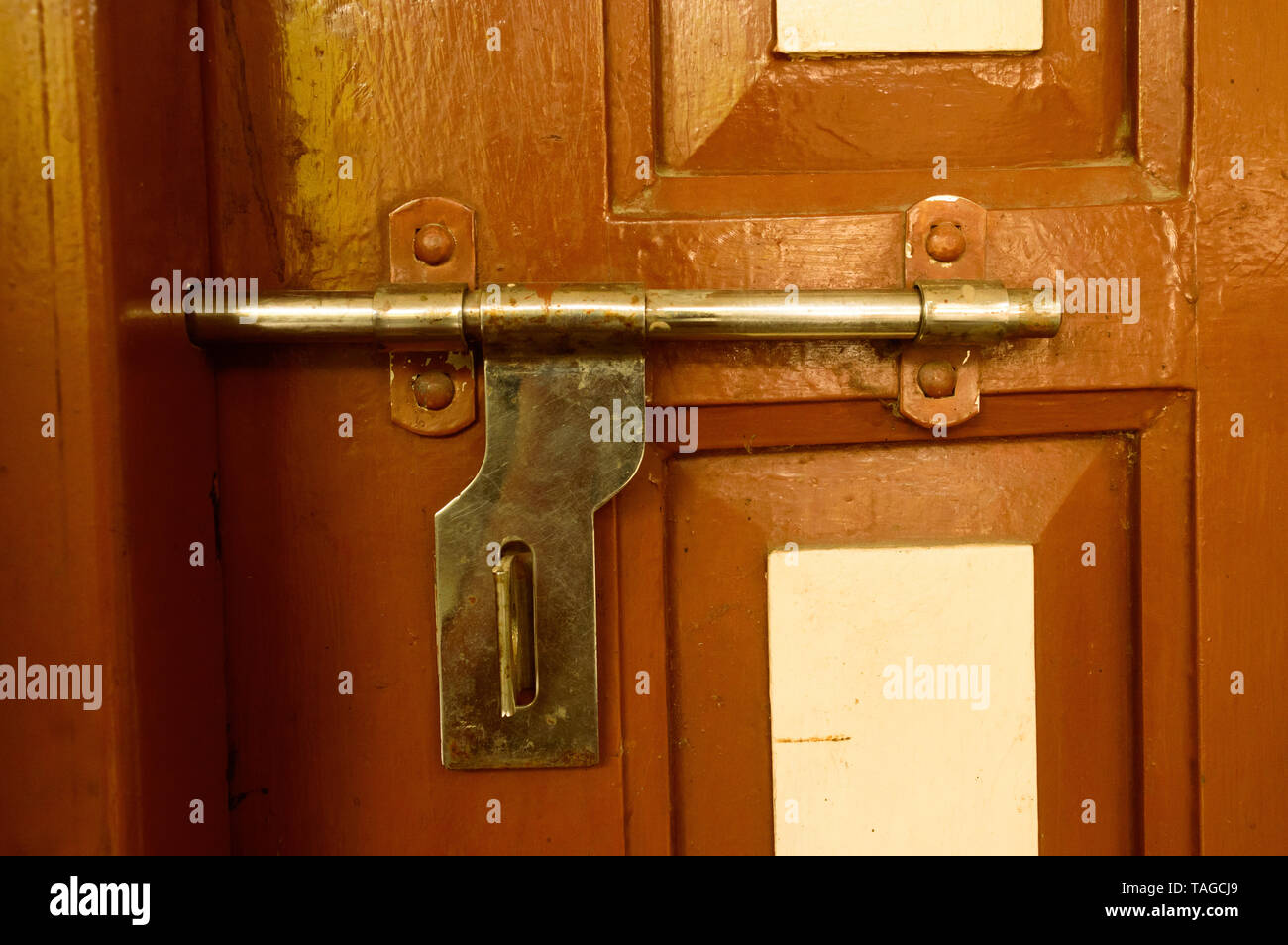Primo piano vista frontale esterna ruvida arrugginito vecchio legno marrone maniglia della porta di ferro metallico con telaio in stile grungy e di buona consistenza di una piena porta chiusa o Foto Stock