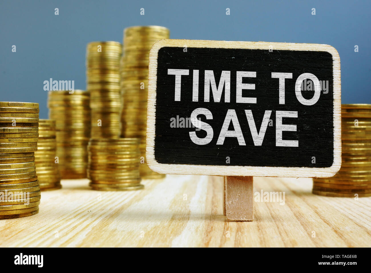Pila di monete e segno del tempo per risparmiare denaro. Foto Stock