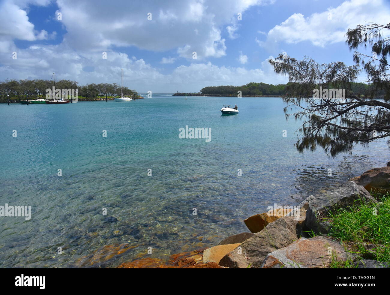 Barca sul fiume Mooloolah su un soleggiato ma giorno nuvoloso. Parete di roccia lungo il fiume Mooloolah (Sunshine Coast, Queensland, Australia). Yacht ormeggiati nel marin Foto Stock