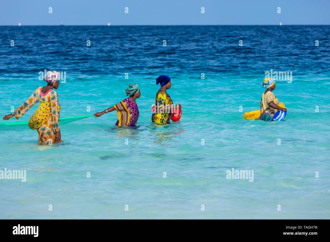 Kendwa, Zanzibar-March 4, 2019 : donna in abiti tradizionali con rete da pesca in mare presso la spiaggia di Kendwa Foto Stock