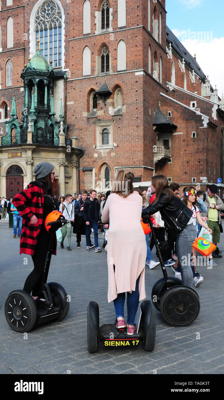 I giovani su Segways incontro a Cracovia dalla Piazza della Città Vecchia, Rynek Glowny, davanti a Santa Maria la Basilica. Foto Stock