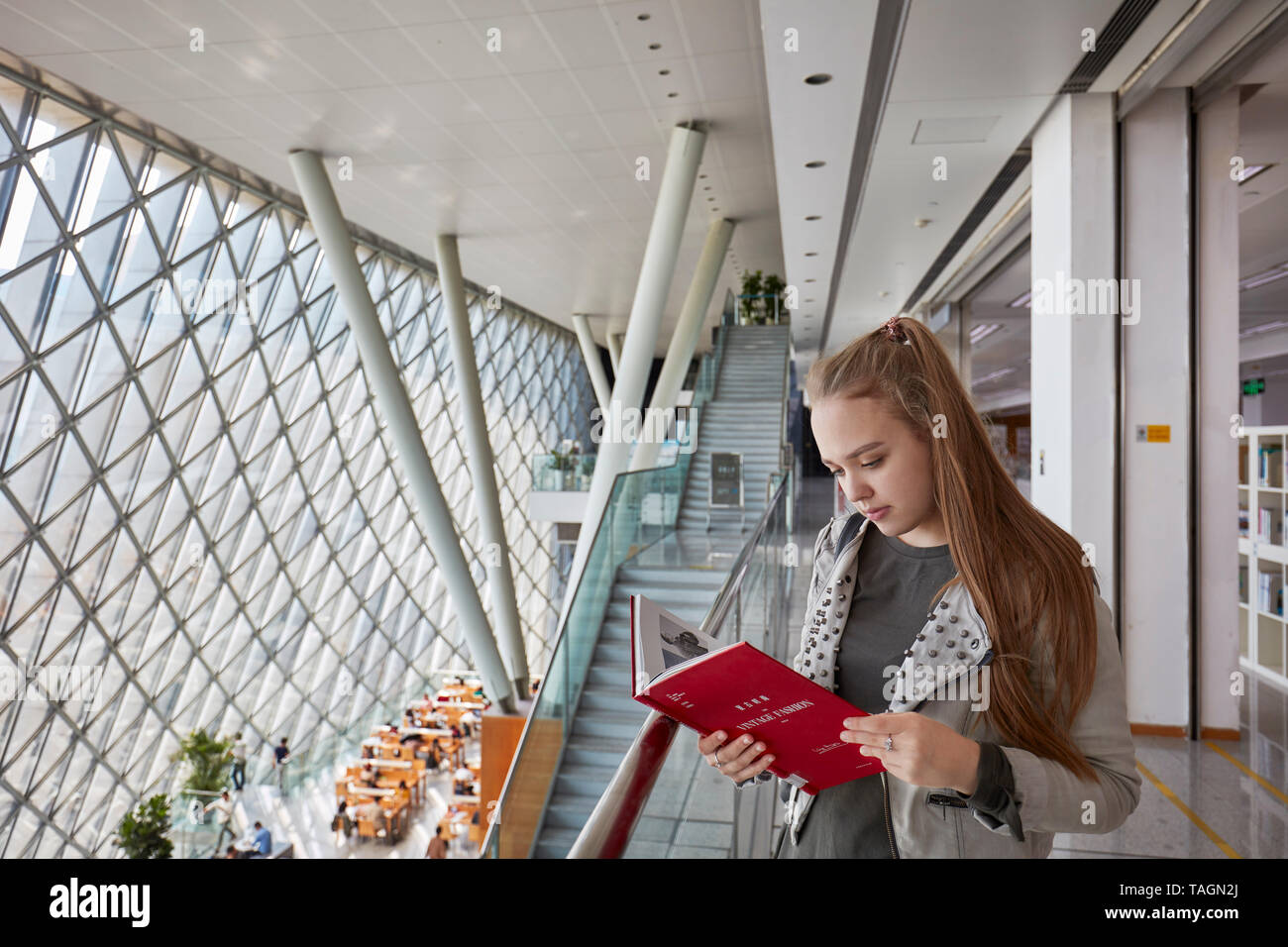 La giovane ragazza caucasica legge un libro nella biblioteca di Shenzhen al Centro Culturale di Shenzhen. Shenzhen, Provincia di Guangdong, Cina. Foto Stock