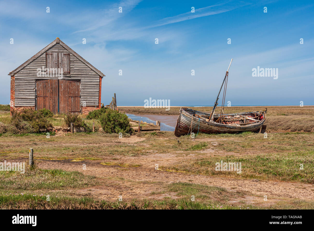 Vista del vecchio fienile di carbone e la vecchia barca di legno a thornham porto sulla Costa North Norfolk Foto Stock