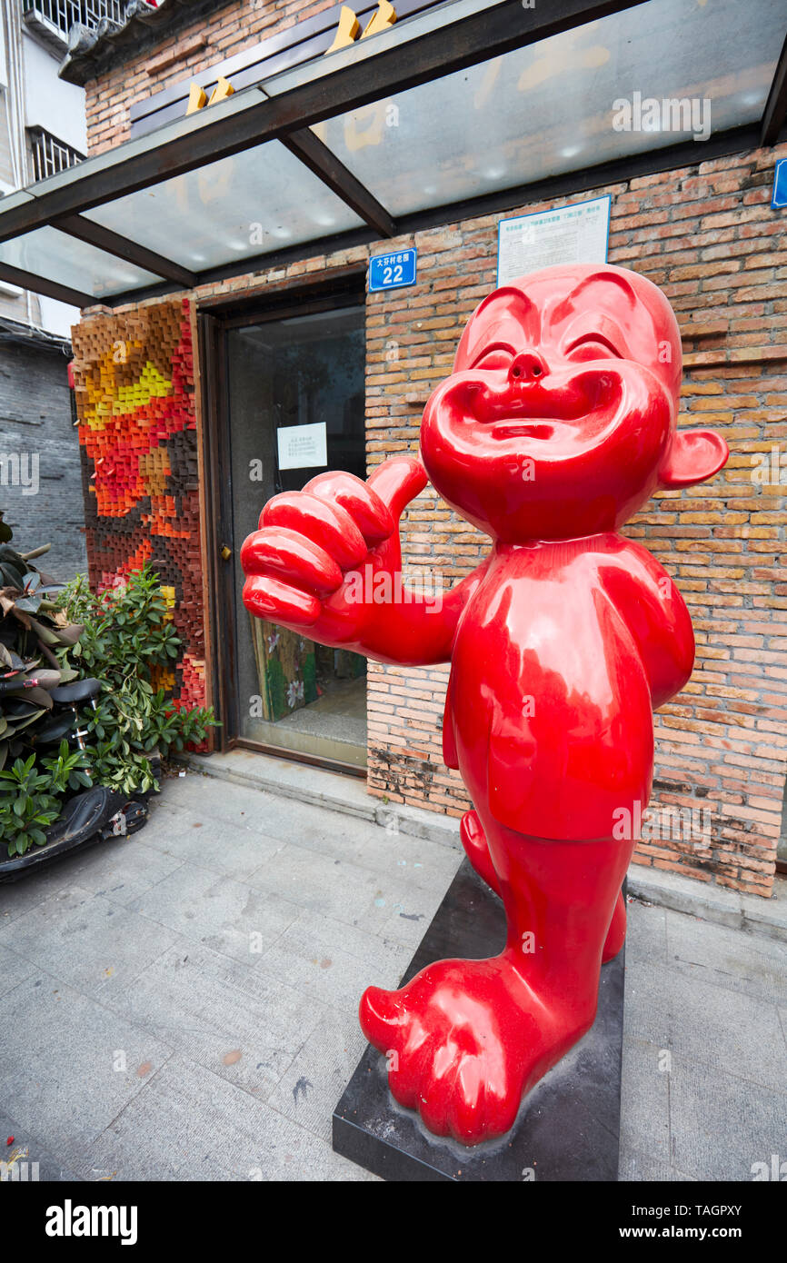 Rosso comico figura mostra un pollice-up gesto a galleria locale entrata nel Villaggio della Pittura ad Olio Dafen. Shenzhen, Provincia del Guangdong, Cina. Foto Stock