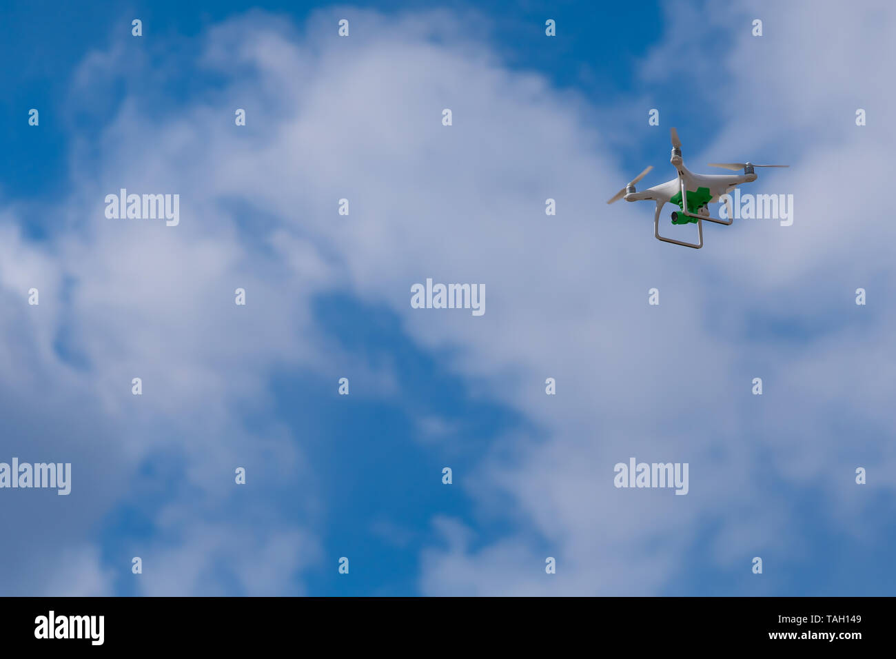 Flying drone bianco con una telecamera verde sullo sfondo di offuscata cielo blu con nuvole. Foto, video o patrol da un altezza. Foto Stock