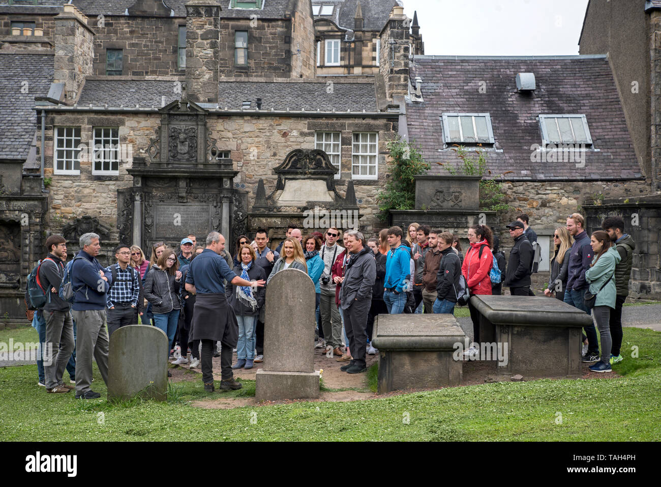 I turisti in un tour a piedi di Edimburgo visitano la tomba di John Grey, il maestro dei Greyfriars Bobby, a Greyfriars Kirkyard. Foto Stock