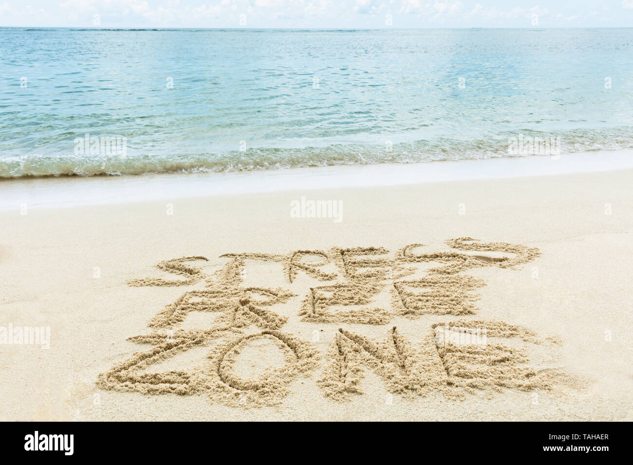 Close-up della zona senza stress Scritta sulla sabbia vicino al mare in spiaggia Foto Stock