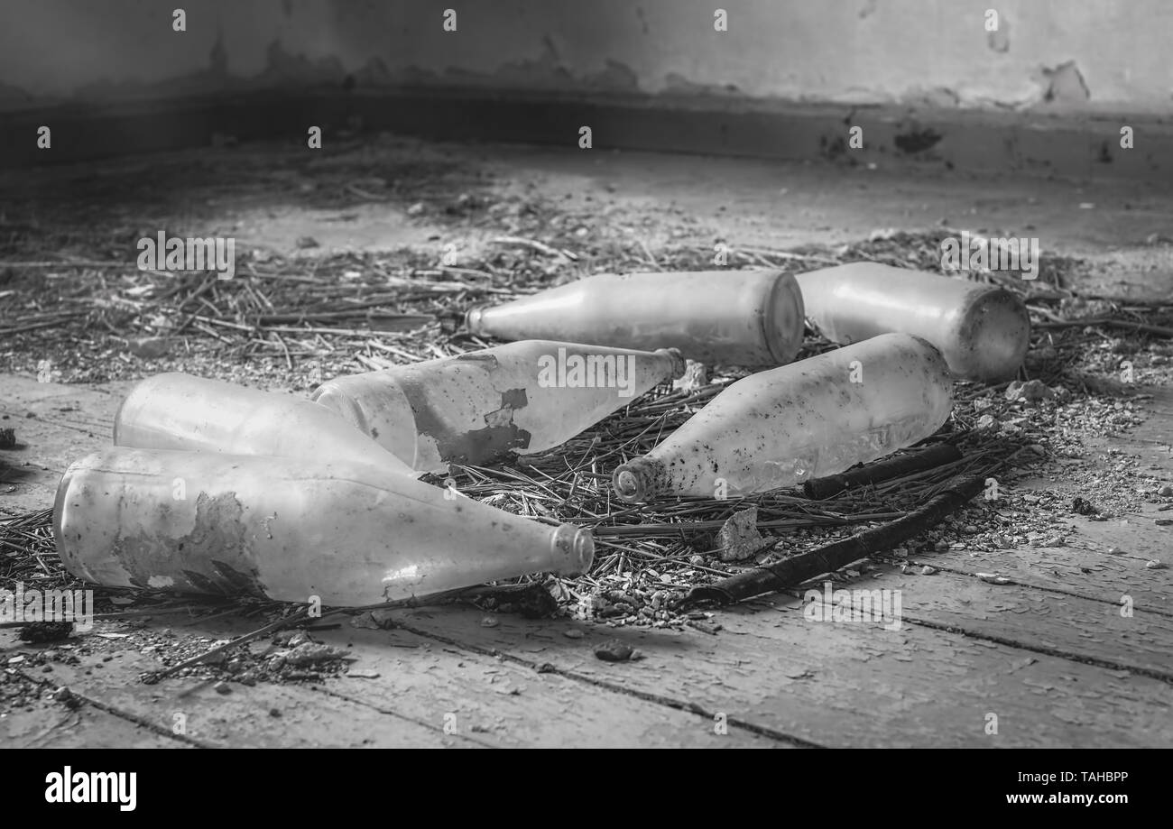 Polverose bottiglie sul pavimento in una casa abbandonata Foto Stock