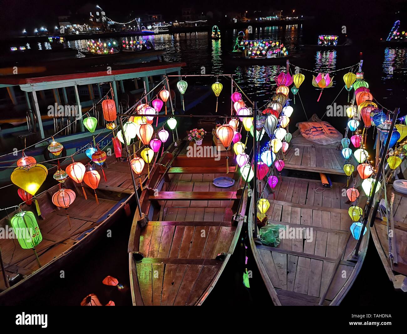 Vista notturna di colorate lanterne appese su barche di legno vicino al lungofiume all'interno di Hoi An old town, Vietnam Foto Stock