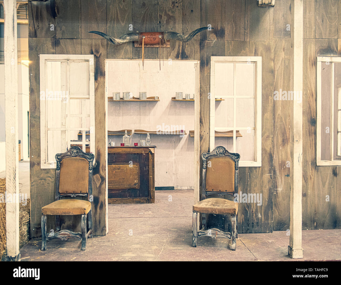 Lunghezza piena vista frontale del saloon con sedie, bancone bar bottiglie e contenitori di vetro senza persone old wild west concept Foto Stock
