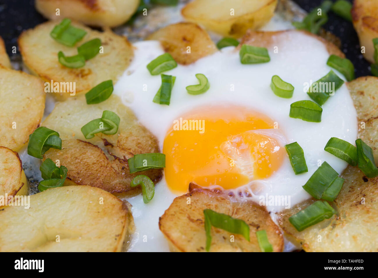 Uova fritte e patate con un trito di erba cipollina Foto Stock