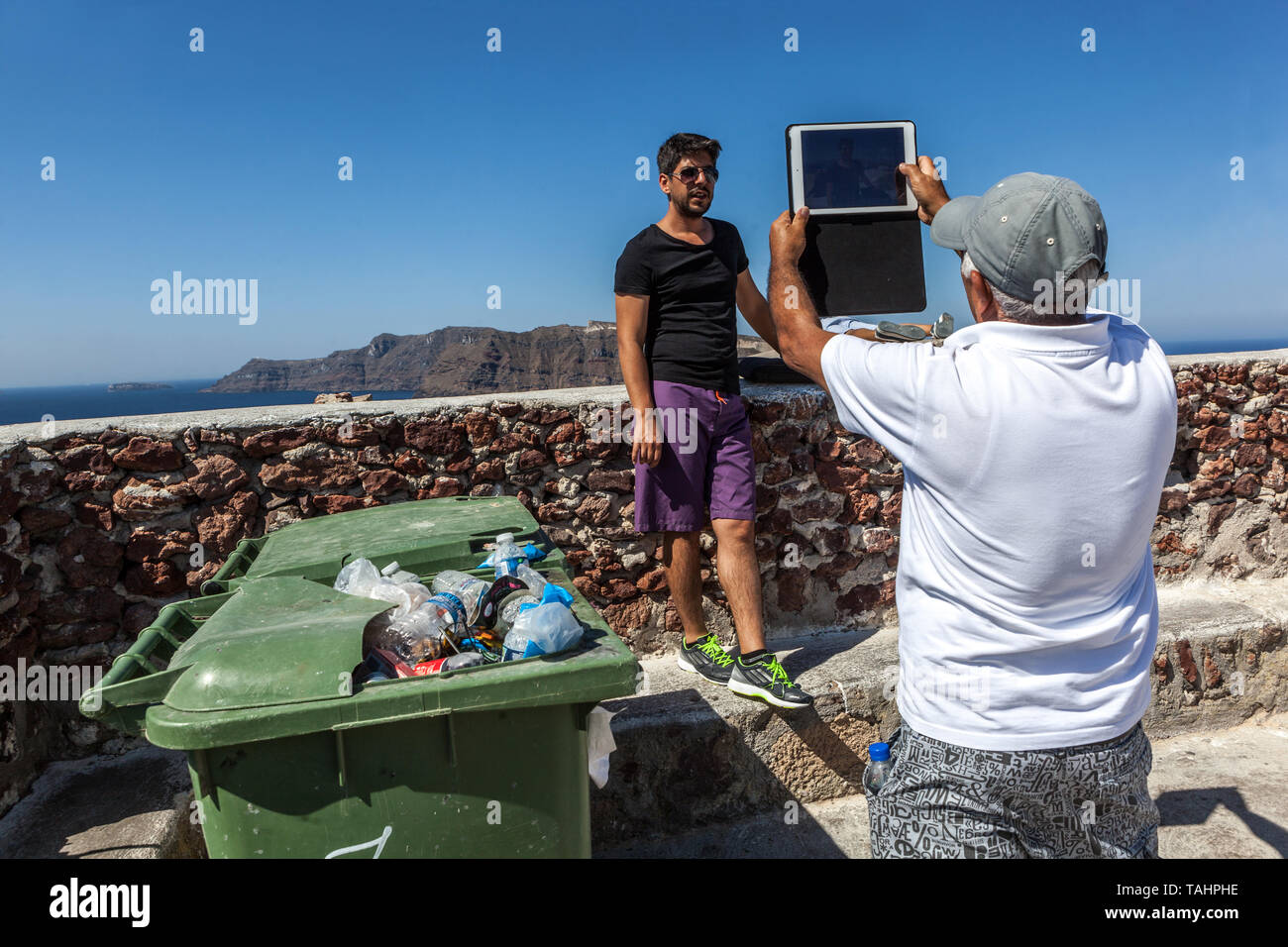 Grecia Santorini Oia Castello, persone, uomo fare foto su un tablet, bidoni della polvere sono fuori di colpo Foto Stock