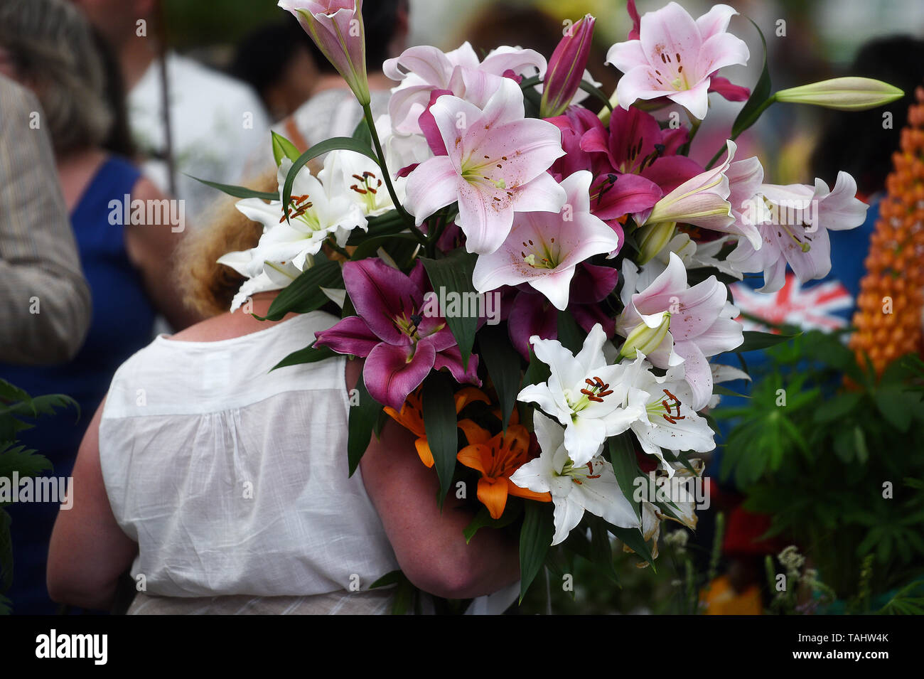 Un visitatore porta un mazzetto di gigli dopo il grande impianto sell-off della RHS Chelsea Flower Show presso il Royal Hospital Chelsea, Londra. Foto Stock