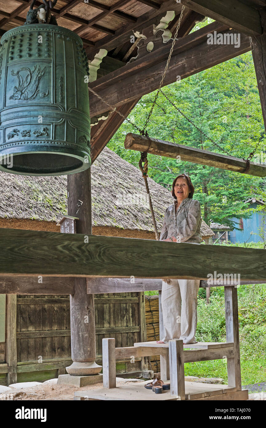 Asian Lady tirando la corda per suonare il campanello al Belfry presso il tempio Daishoin, l'isola di Miyajima, Giappone Foto Stock