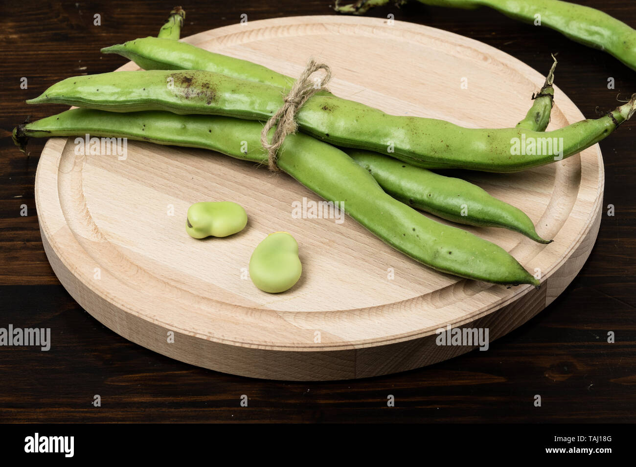 Le fave fresche sul tagliere di legno e legno scuro tabella Foto Stock