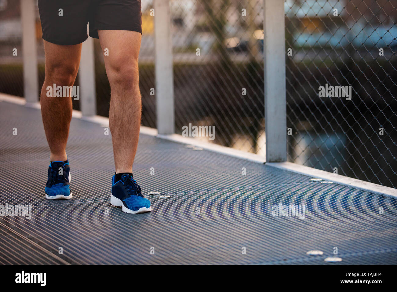 Giovane uomo sportivo gambe in esecuzione all'aperto lungo un ponte al mattino. Auto conquistando superare ostacoli e vincere. Uno stile di vita sano concetto. Allenamento jo Foto Stock