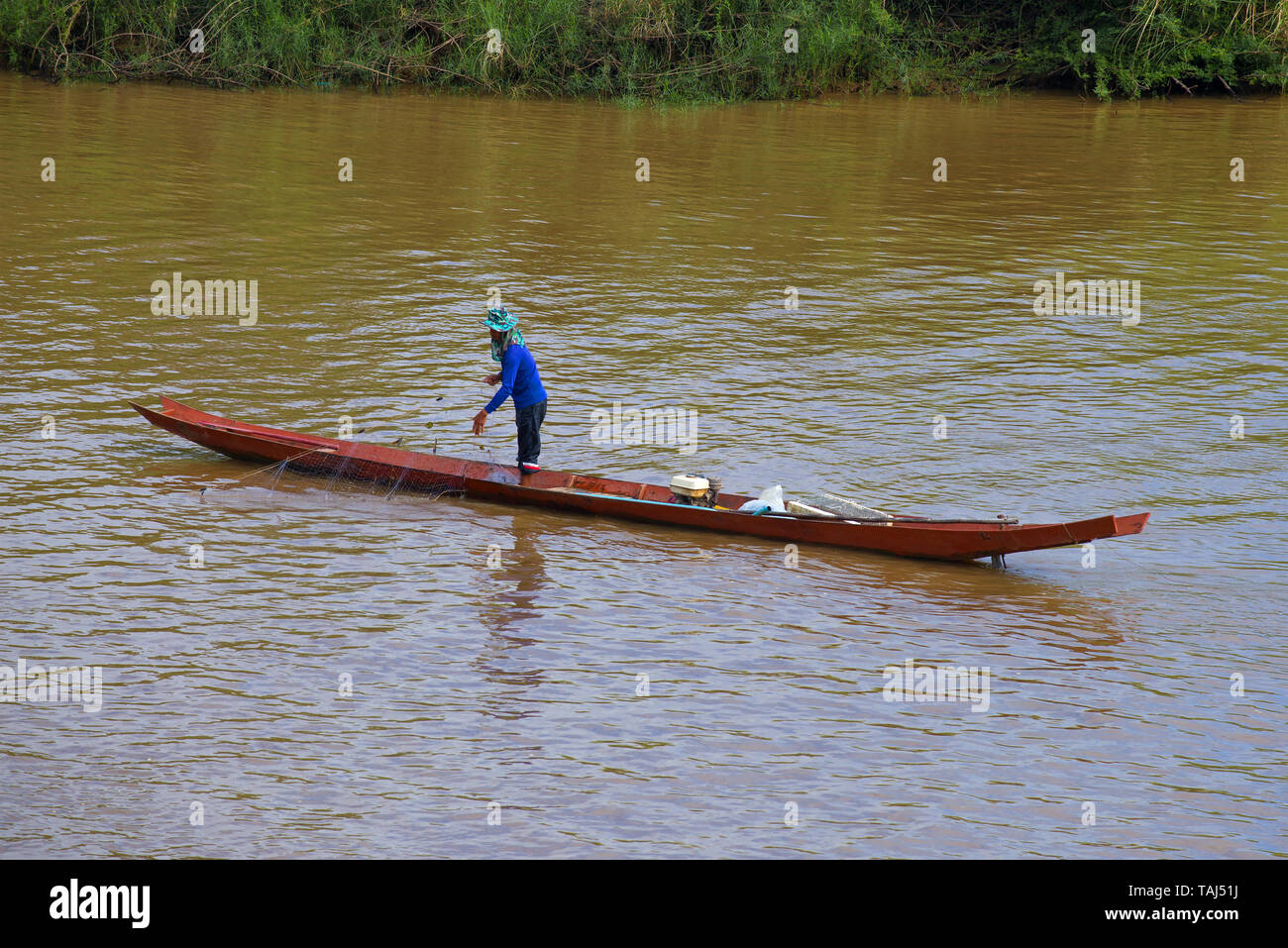 Pescatore con un netto su una barca di legno sul fiume Ruak. Thailandia del Nord Foto Stock
