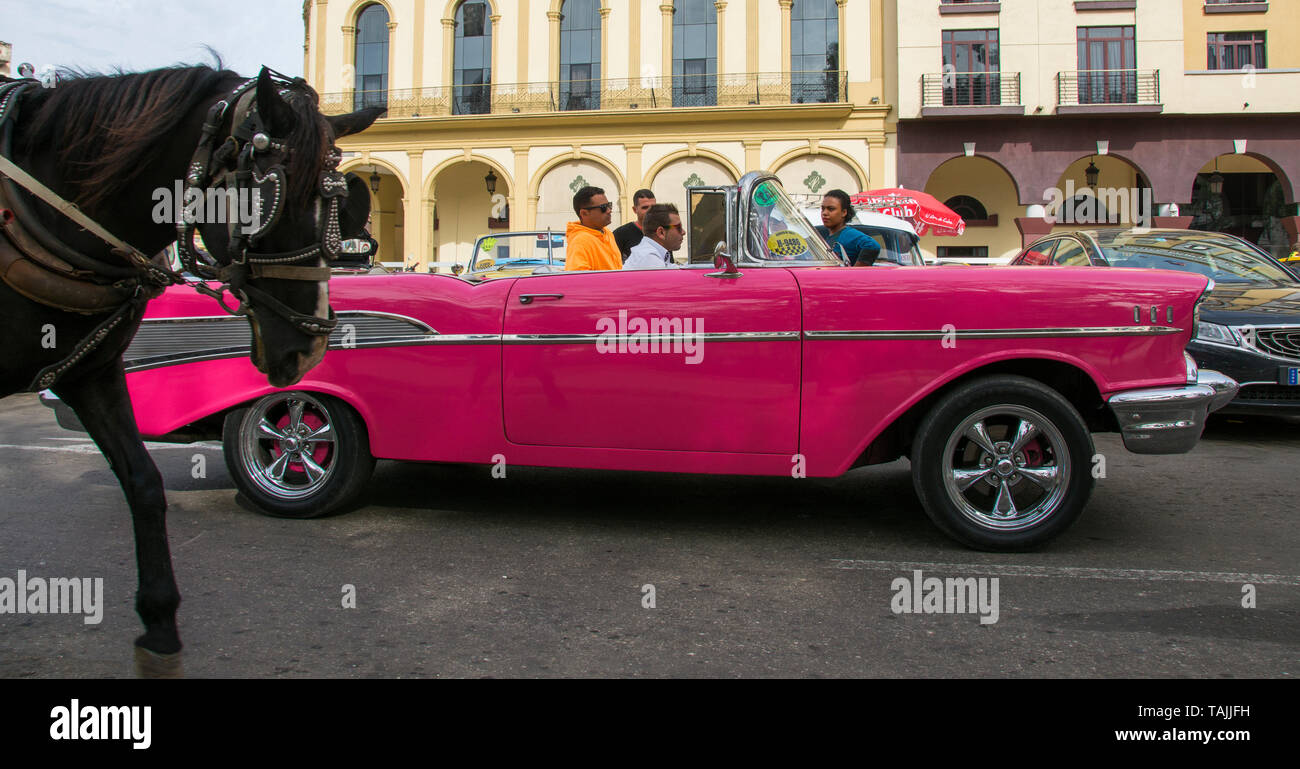 L'Avana, Cuba - una carrozza trainata da cavalli passa da un taxi di fronte all Hotel Parque Central. Classic auto americane degli anni cinquanta, importati prima di Stati Uniti e Foto Stock