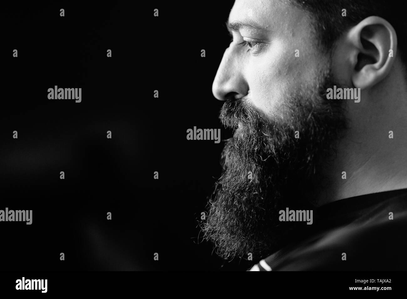 Bianco e nero ritratto di uomo barbuto, sfondo nero Foto Stock