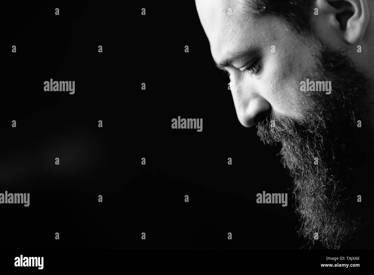 Bianco e nero ritratto di uomo barbuto, sfondo nero Foto Stock
