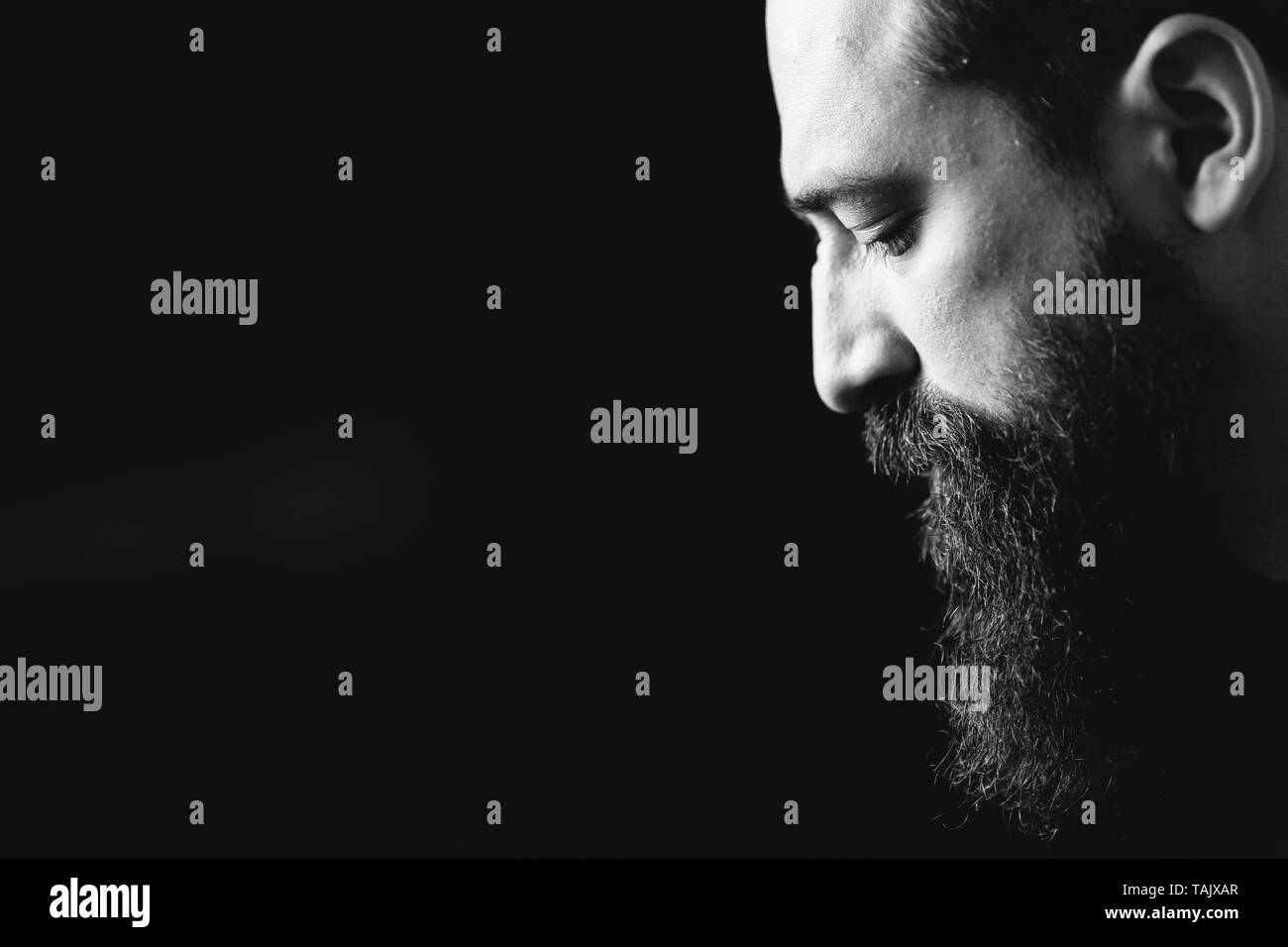 Bianco e nero ritratto di uomo barbuto, sfondo nero Foto Stock