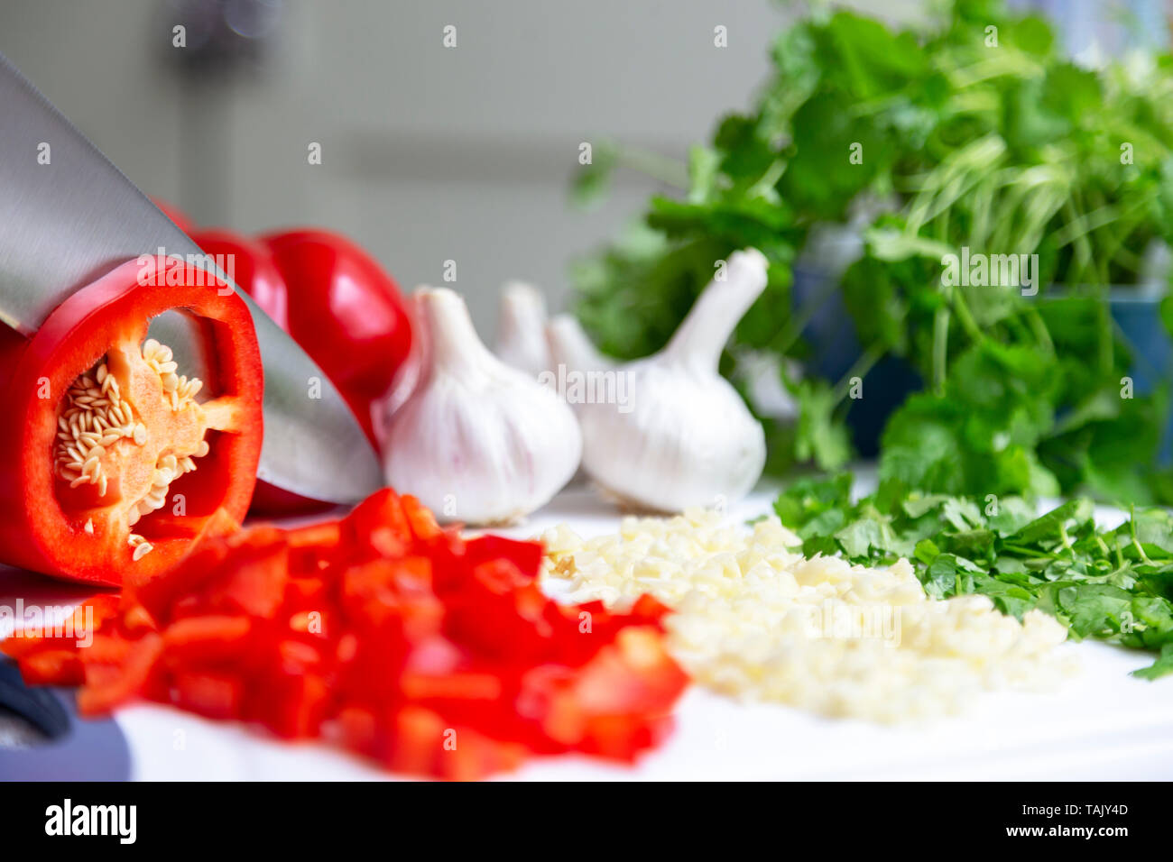 Il taglio della lama peperone rosso con bulbi di aglio e coriandolo Foto Stock