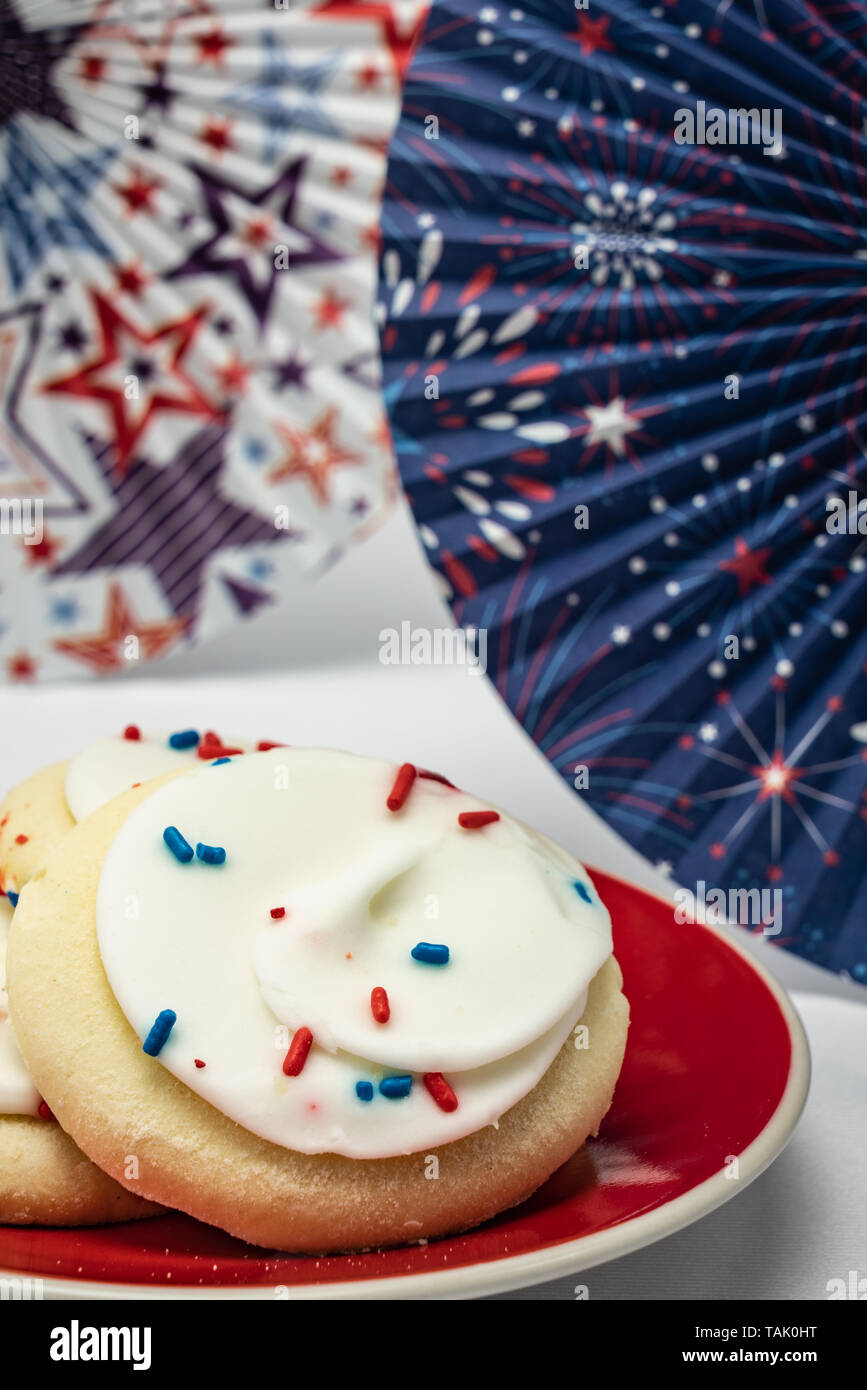 I cookie di zucchero con glassa alla vaniglia e di rosso e di blu spruzza in una messa a fuoco morbida a tema patriottico sfondo di stelle e fuochi d'artificio Foto Stock