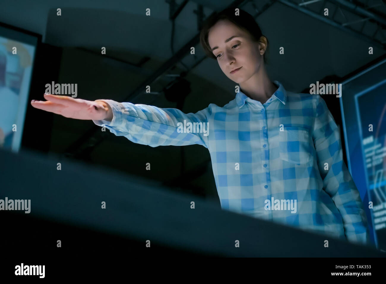 Donna che utilizza la visualizzazione interattiva senza toccare la tecnologia di controllo Foto Stock