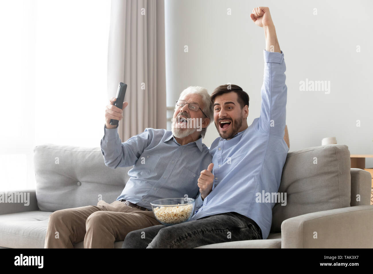 Emozionato anziani papà e figlio tifo guardando la TV gioco insieme Foto Stock