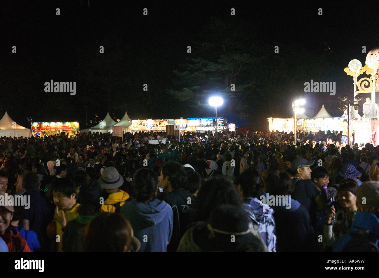 La folla di visitatori intorno alla piazza principale e food court durante la serata di apertura del 2016 Fuji Rock Festival in Naeba, Yuzawa, Niigata, Giappone. Foto Stock