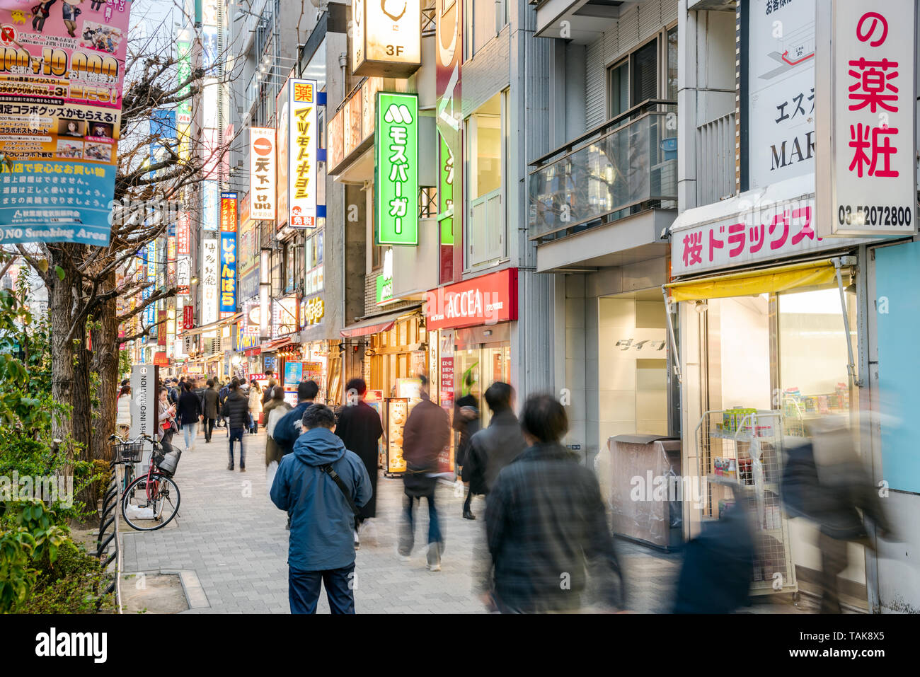 Tokyo, Giappone - 23 Marzo 2019: persone che passeggiano lungo un marciapiede foderato con negozi di elettronica e di un ristorante a Akihabara Foto Stock