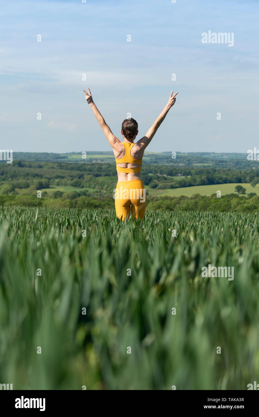 Sportivo da donna con le braccia sollevate in un campo, freedon concetto. Foto Stock
