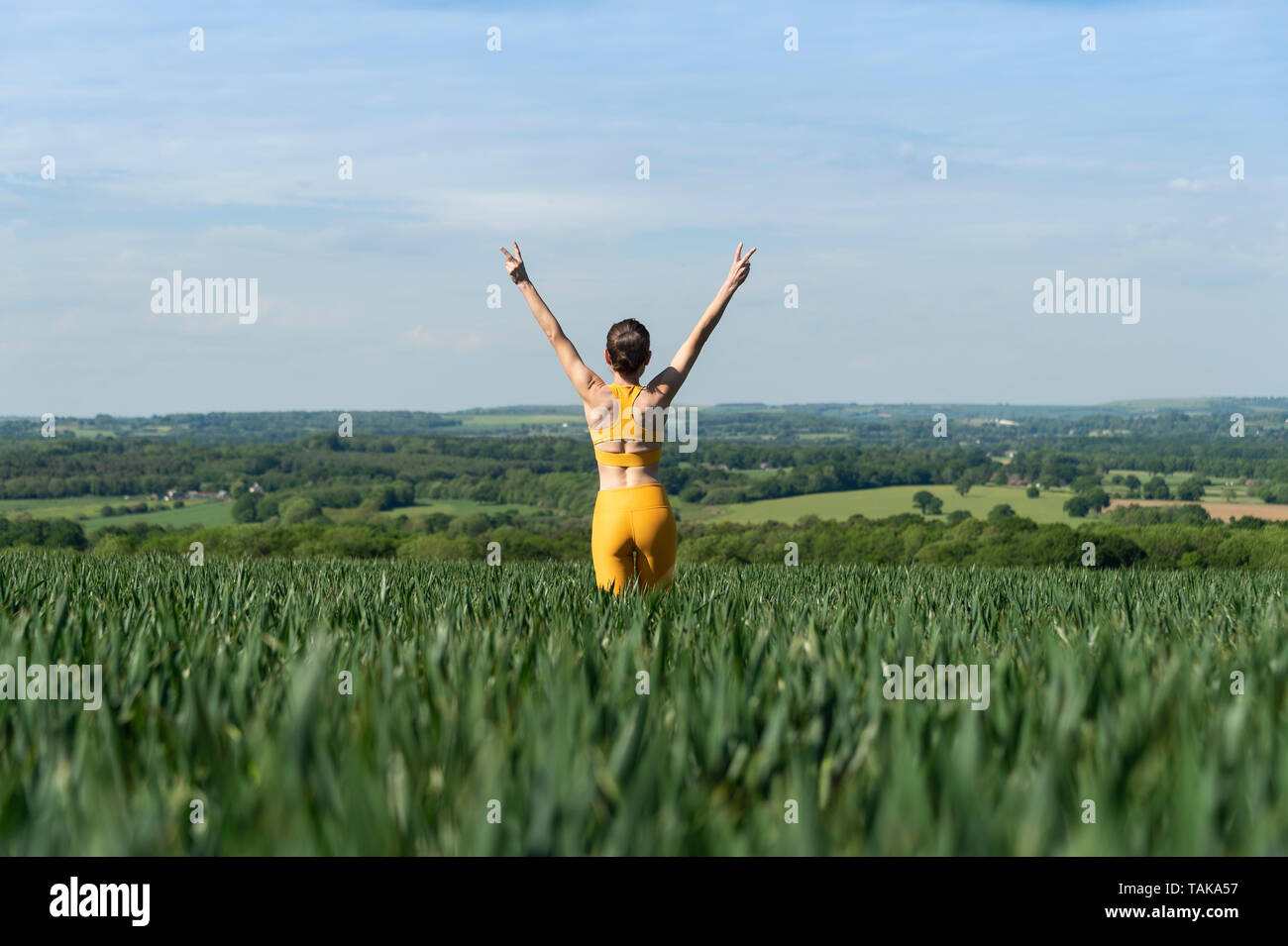 Sportivo da donna con le braccia sollevate in un campo, freedon concetto. Foto Stock