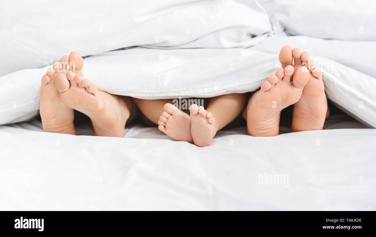 Tre coppie di piedi di famiglia felice a letto Foto Stock