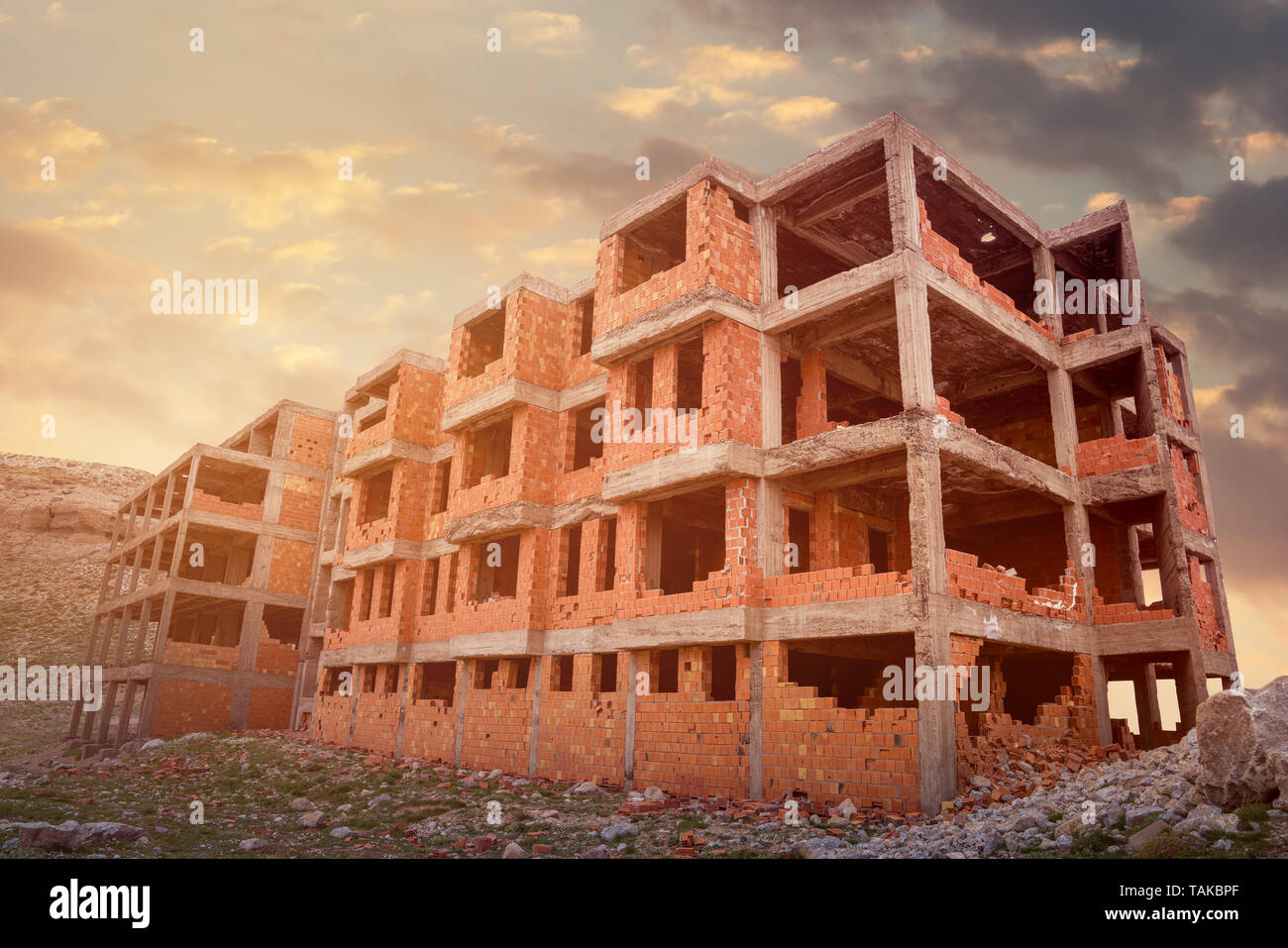 La costruzione dell'edificio sito dal calcestruzzo e mattoni contro il tramonto Foto Stock