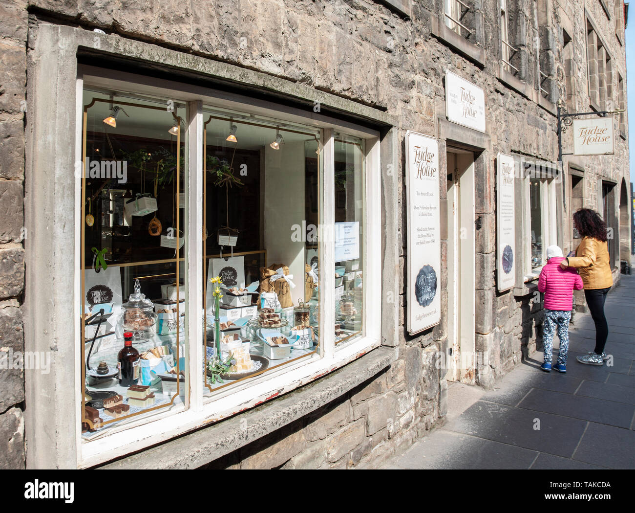 Una donna e bambino guardare in una finestra della casa di Fudge, uno specialista dolciumi venditore sulla Strada Alta / Royal Mile di Edimburgo, Scozia, Regno Unito Foto Stock