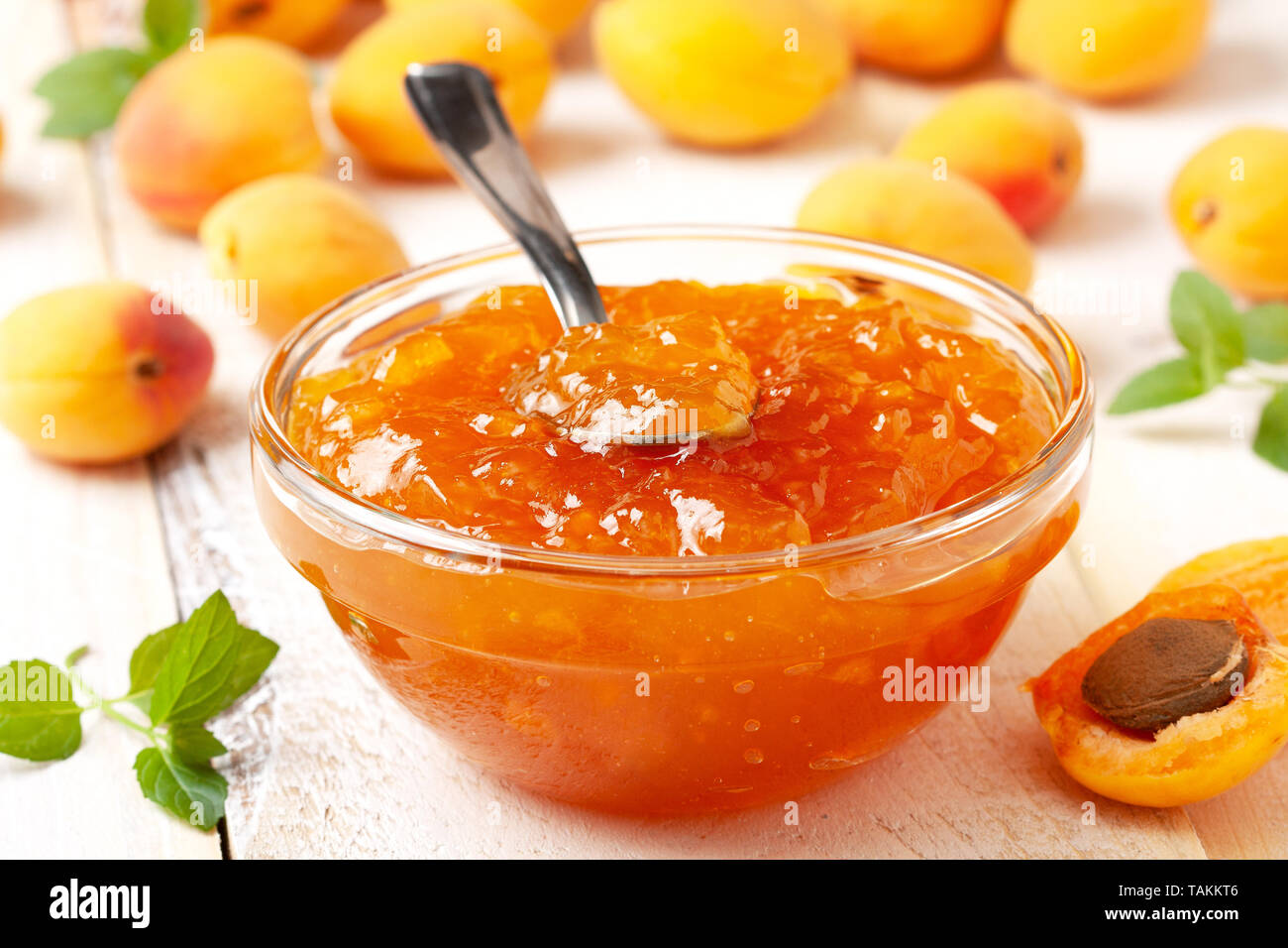 Confettura di albicocche in una ciotola di vetro, fresche Albicocche su uno sfondo di legno di close-up Foto Stock